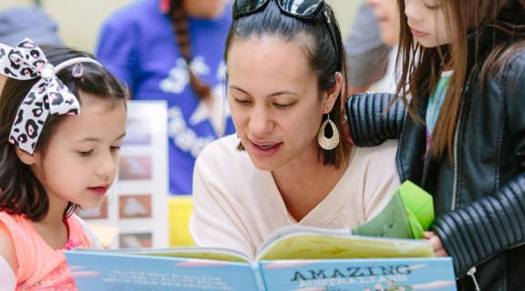 Mother reading a book to her children
