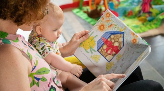 Woman and baby read Hotel for Bees