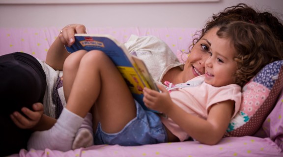 Woman and child reading in bed