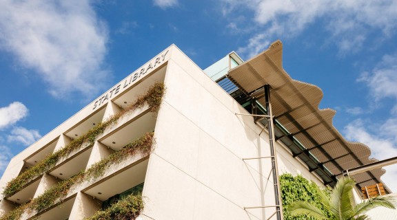 Exterior view of the State Library building from the ground looking upwards with sky and clouds in the background.