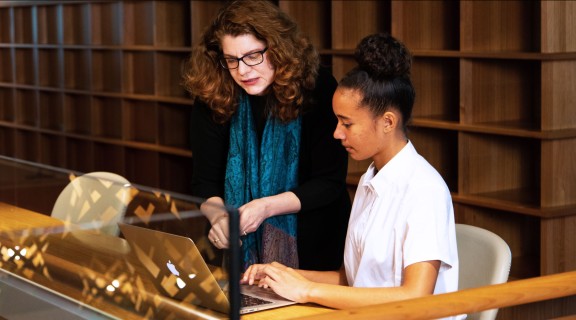 Teacher and student using laptop.