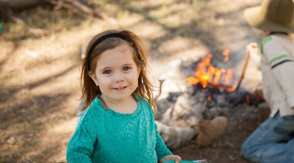 Young girl smiling with a campfire in the background