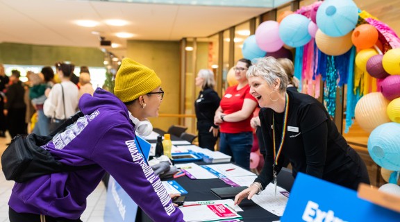 Visitor talking to happy staff member behind a desk during an event at State Library.