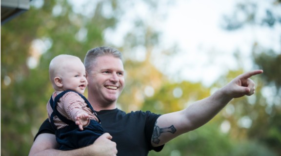 Father holding baby and pointing to object