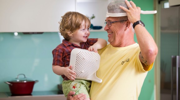 Child and grandfather playing in the kitchen