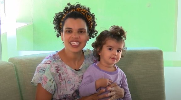 Mother with daughter on her knee sitting on couch