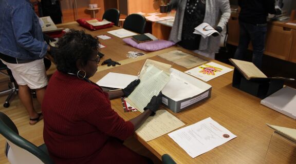 A group of First Nations people at a Black Gloves experience, interacting with collection materials.