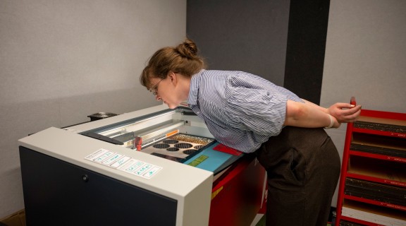 Women looking into view panel of laser cutter machine