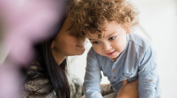 Parent speaking into toddler's ear