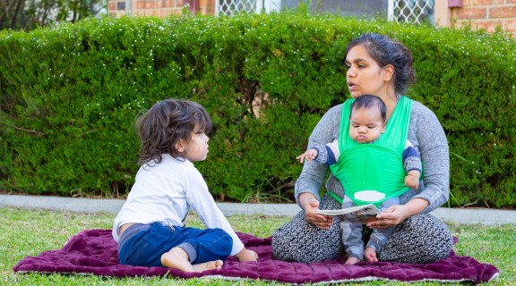Mother and two children sharing a book outside