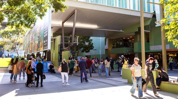 Groups of people walking around the front of State Library.