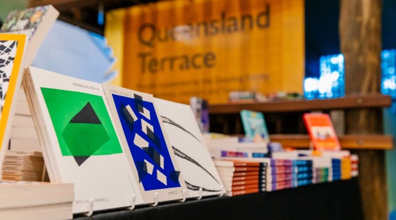 A row of books set up at a bookshop at State Library. The sign behind them read "Queensland Terrace"