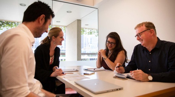 Group of four people at a desk in a meeting room