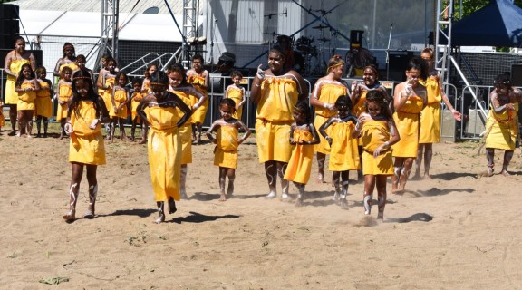 Performance by Yidinji youths dressed in yellow, dancing at Palm Island centenary celebrations, 2018.