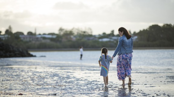 Mother and child walking on beach holding hands