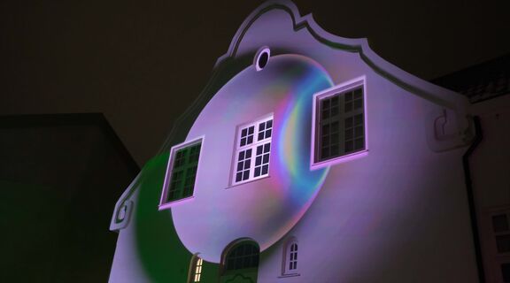 The photo shows some circle of light being projected on a wall. The lights are purple with some rainbow light flares coming through.