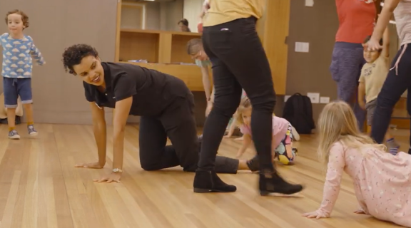 Early childhood educator crawls on the ground with children as part of creative activity.