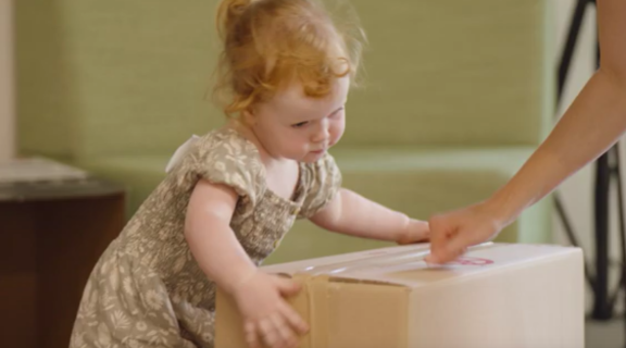 Toddler in green dress picks up box