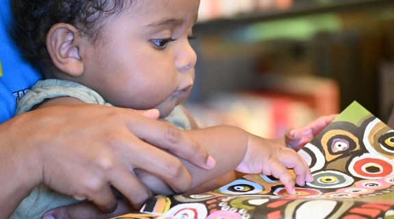 Baby looking through the book My People, 2022, photography by Saltwater People, State Library of Queensland