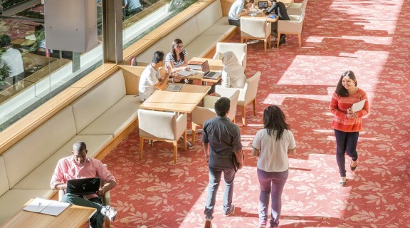 People sitting at desks and walking through the library.