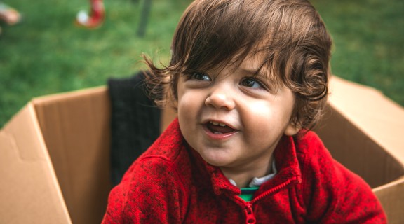 Young child playing with a cardboard box