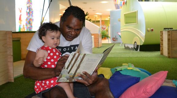 Father and child read a book at the library