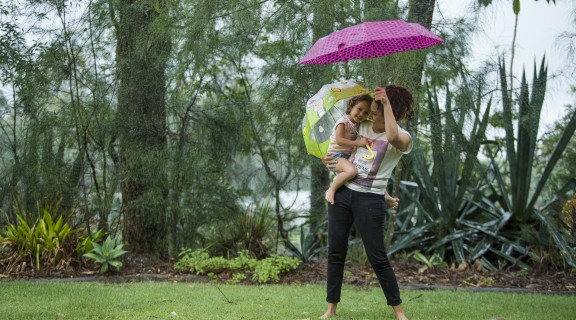Mother and daughter holding umbrellas and dancing in the rain