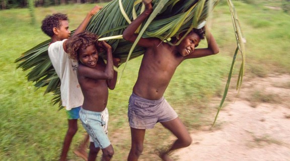 Boys carrying a bundle of cabbage palm leaves