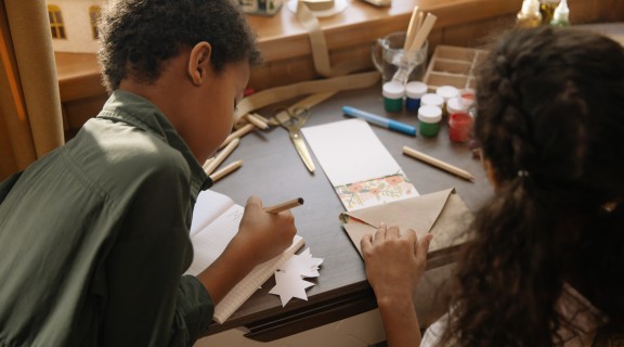 Brother and sister writing cards together
