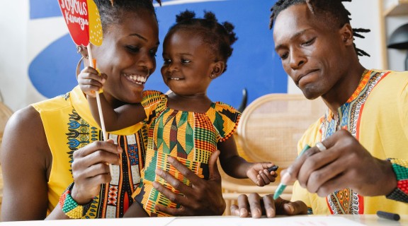 Parents and daughter celebrating Kwanzaa in traditional dress