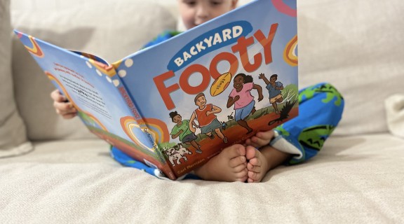 Child reading Backyard Footy