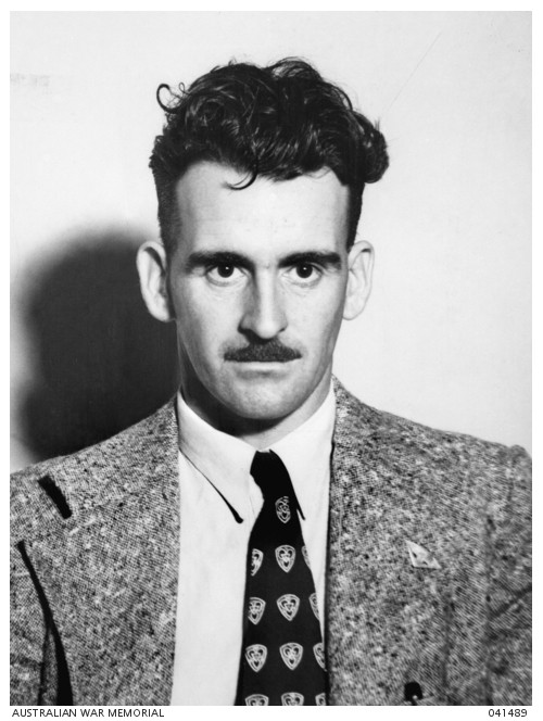 Man with short dark hair and moustache wearing jacket and tie