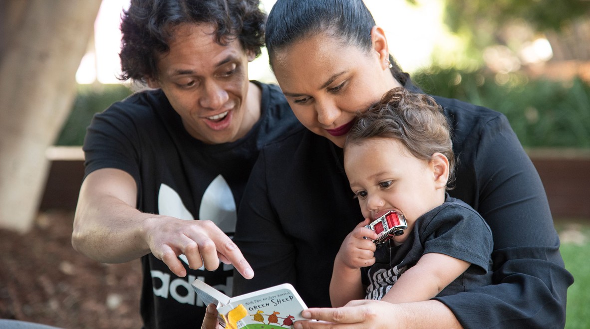 Parents reading a book to a happy child