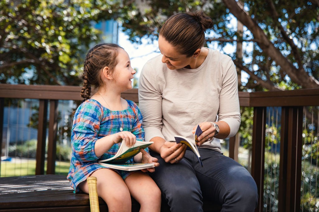 Ash Barty, Australian tennis player, reading to a young child while sitting outside.