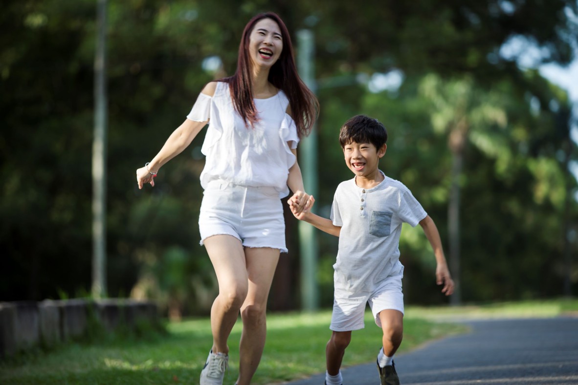 Mother and son running outside hand-in-hand