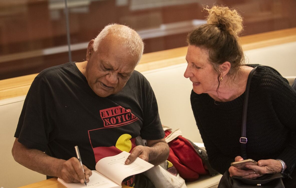 Poet Uncle Lionel Fogarty signing his book for a visitor