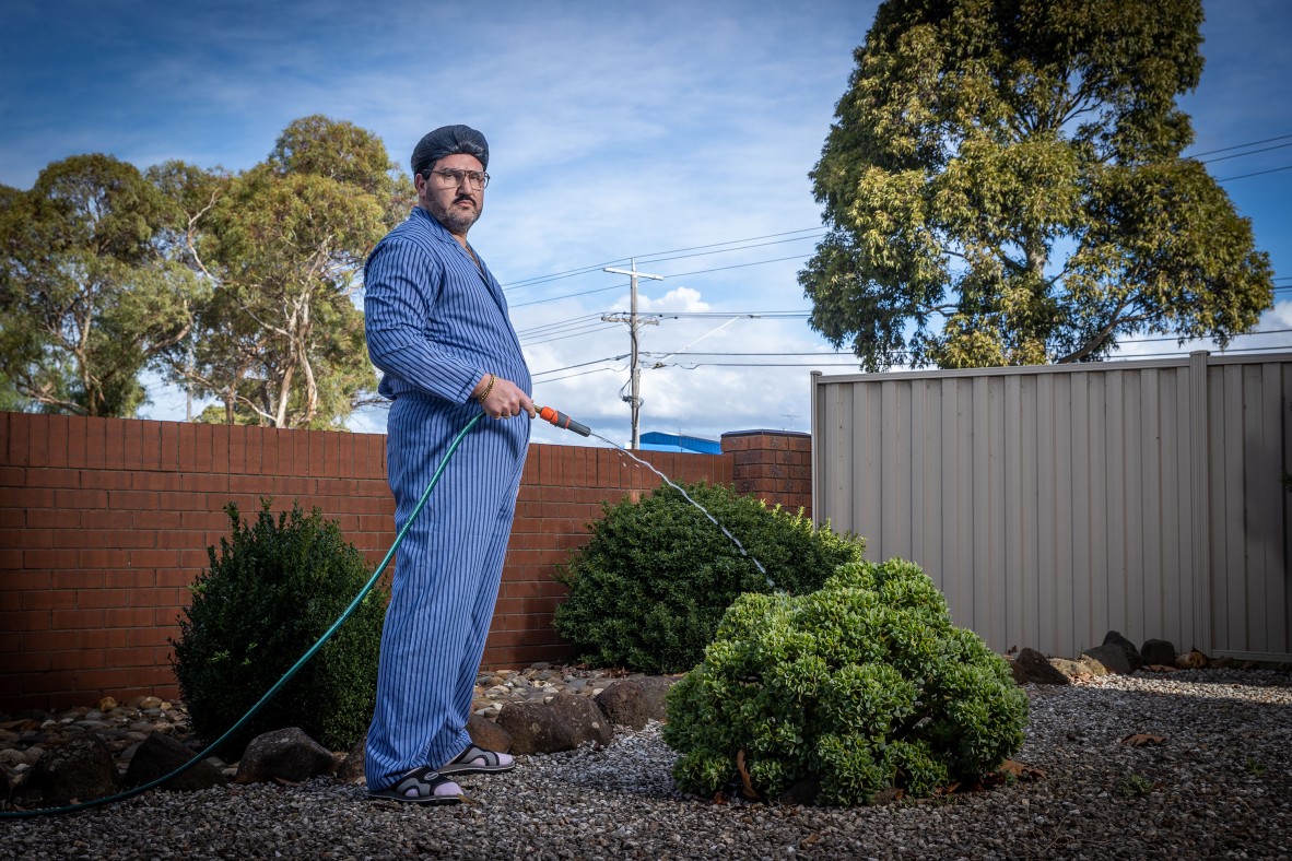 A photo of a man watering plants in a yard