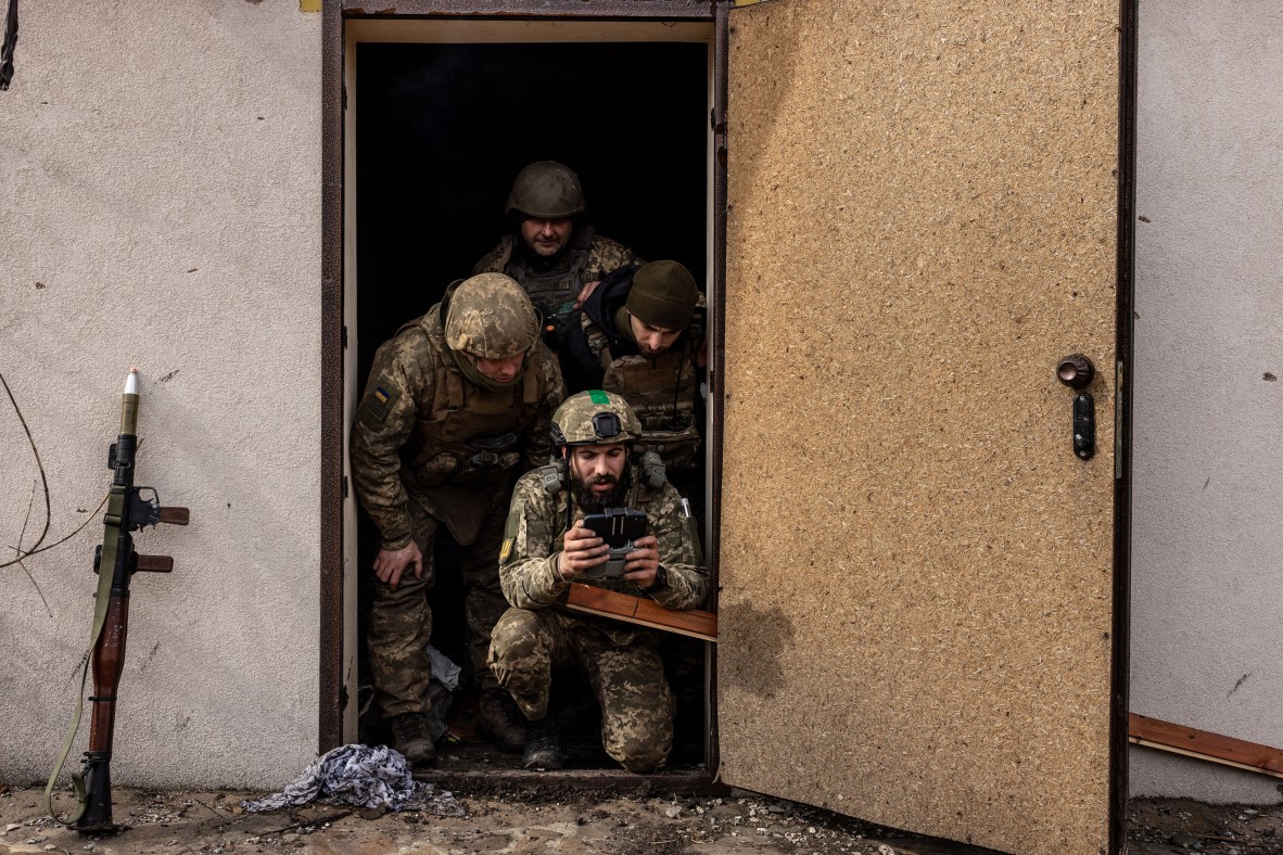 A photo of soldiers in a doorway holding a drone controller