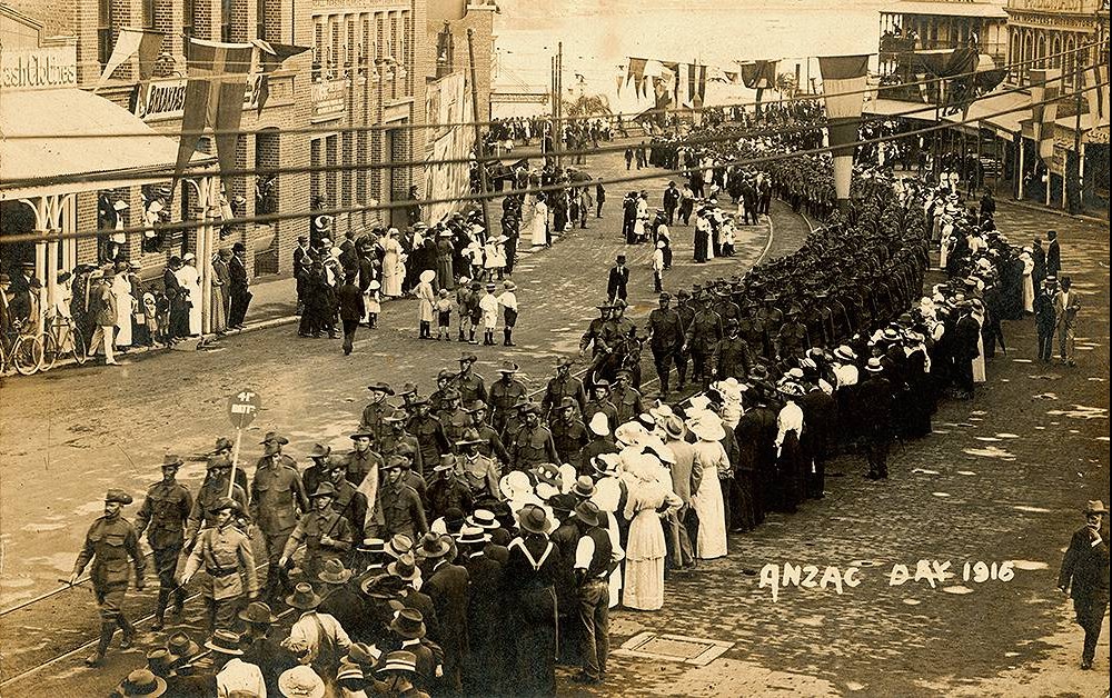 A sepia photo of people lining the streets of Brisbane watching soldiers march during the first Anzac Day in 1916
