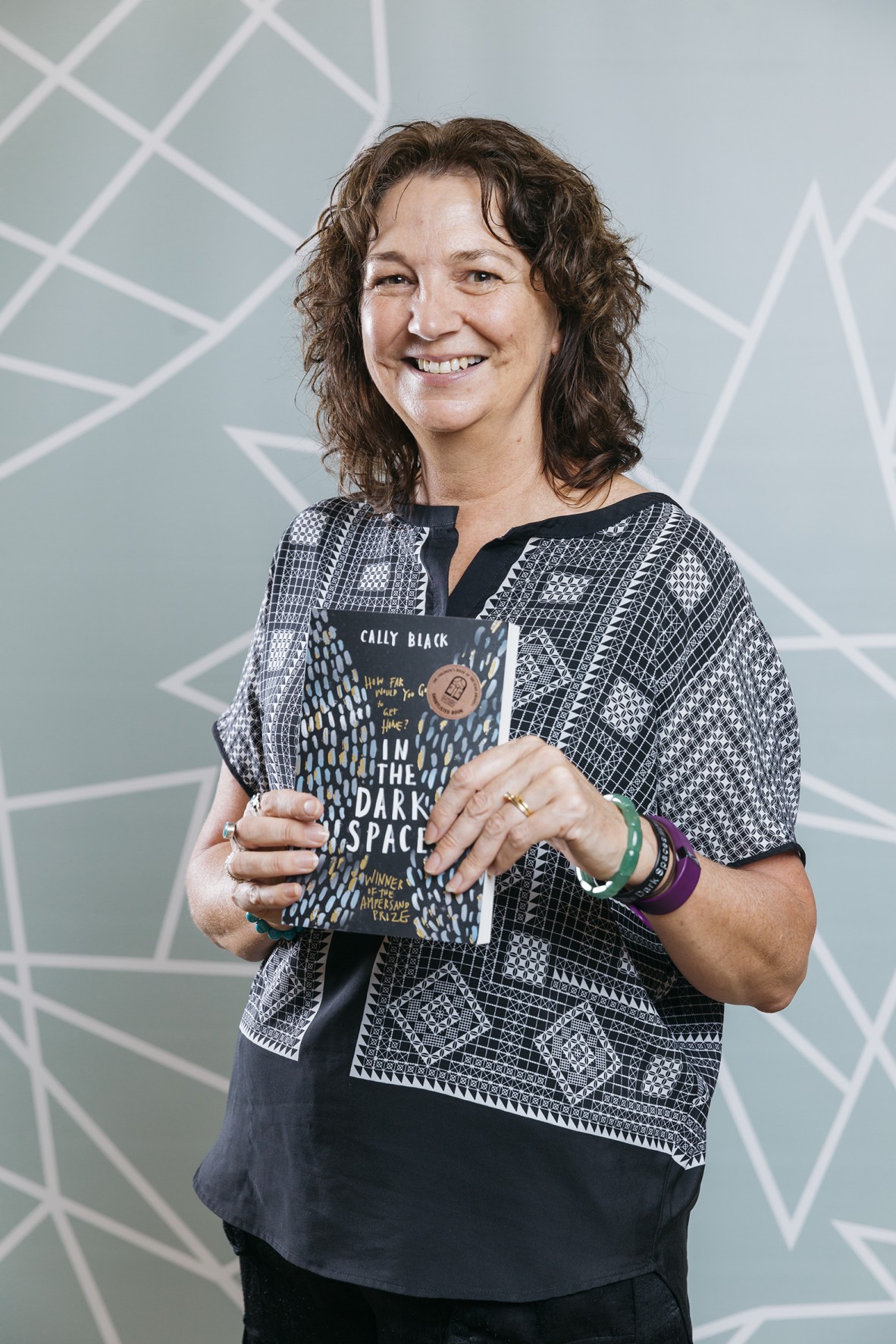 Cally Black holding her book "In the Dark Spaces"