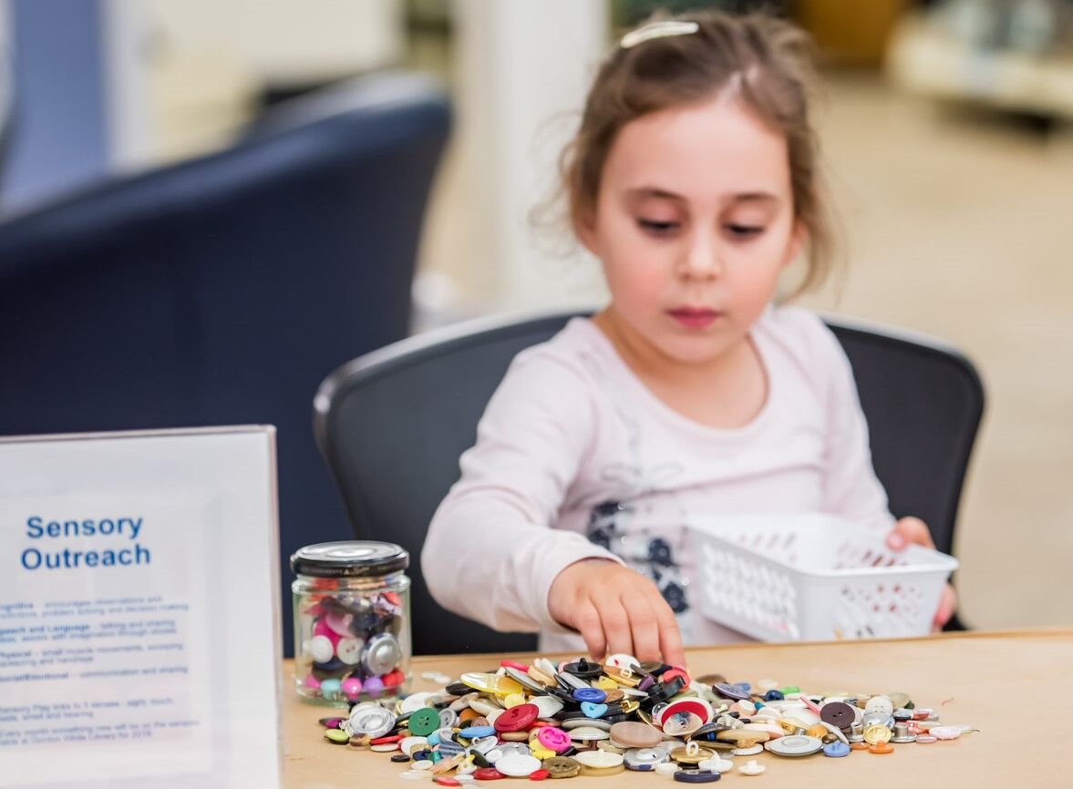 Girl plays with buttons collection in sensory space