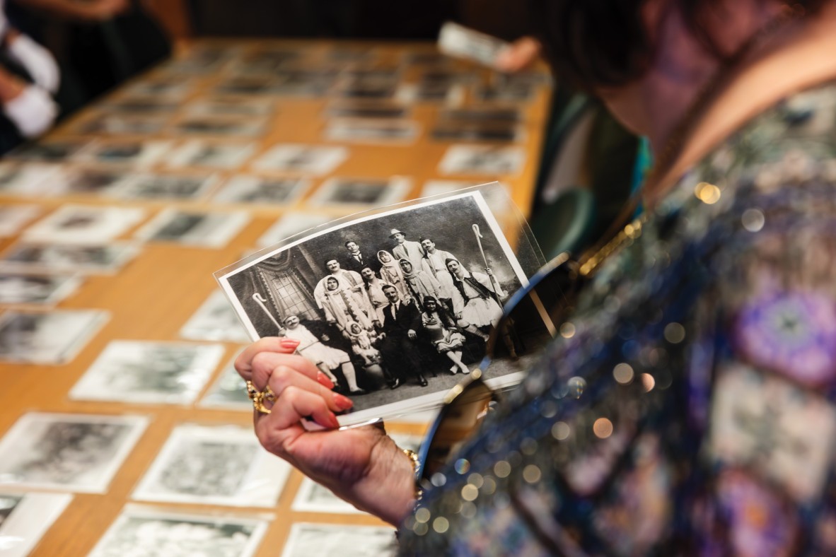 Person holding an old black and white photograph of a group of people. 