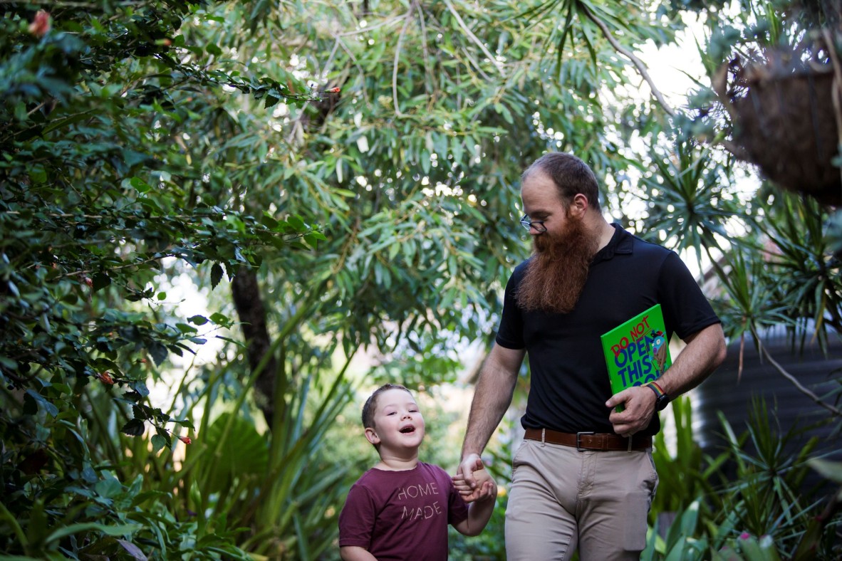 Father and son talk to each other while walking in the backyard.