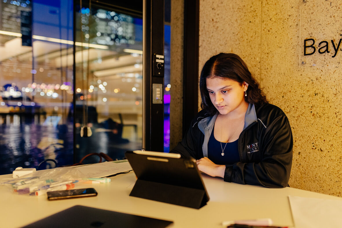 young person sitting at a desk look at an ipad