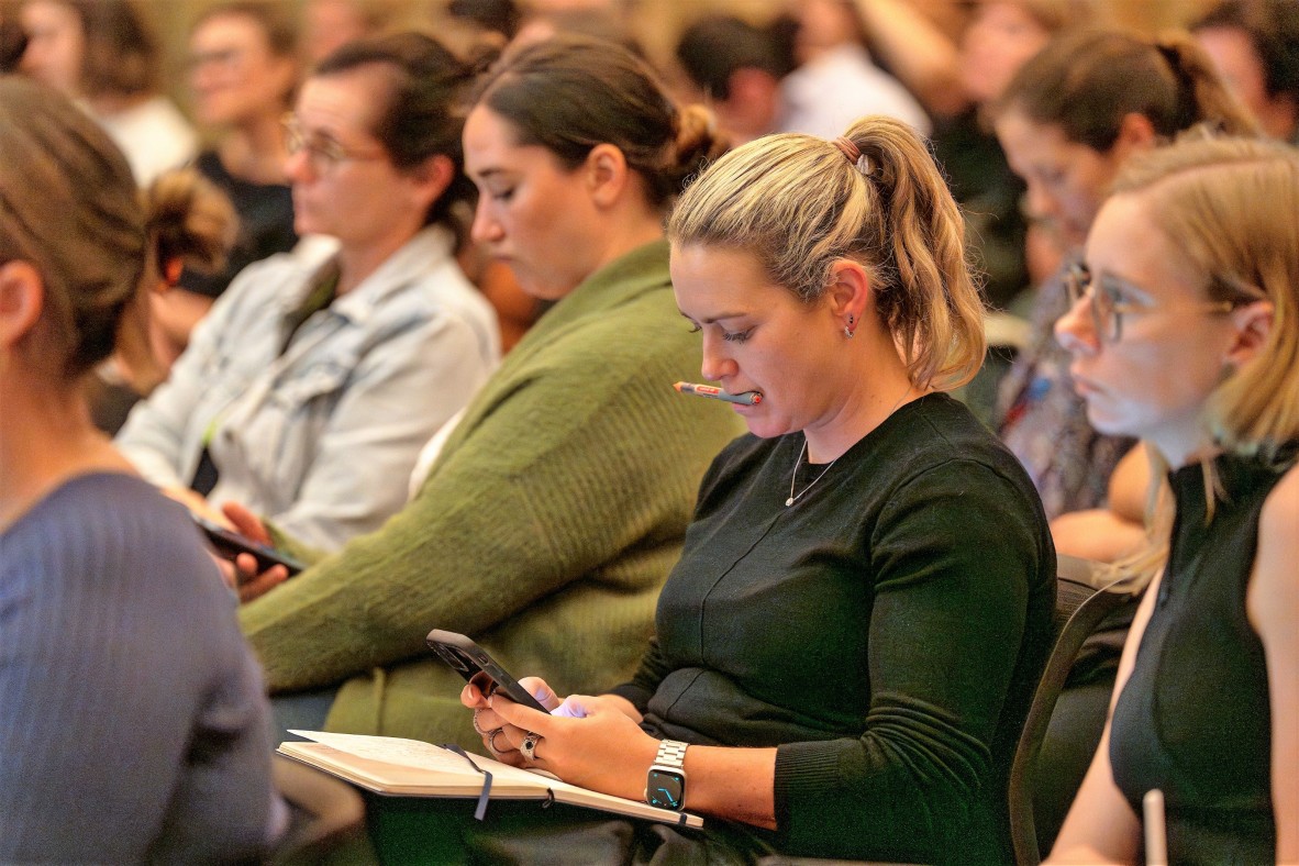 using Slido at an event a woman uses her device, holding her pen in her mouth