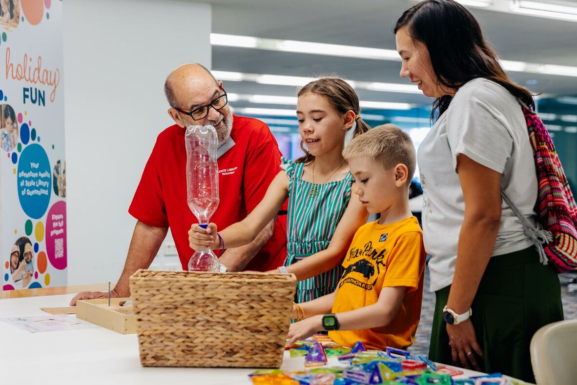 A volunteer helping family conduct a hands-on science activity at the library.