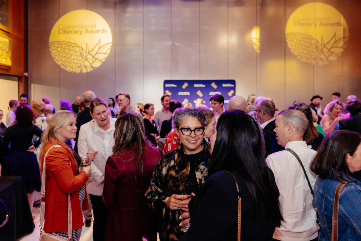 A large crowd of people mingling at a nighttime reception event; two lights say Queensland Literary Awards