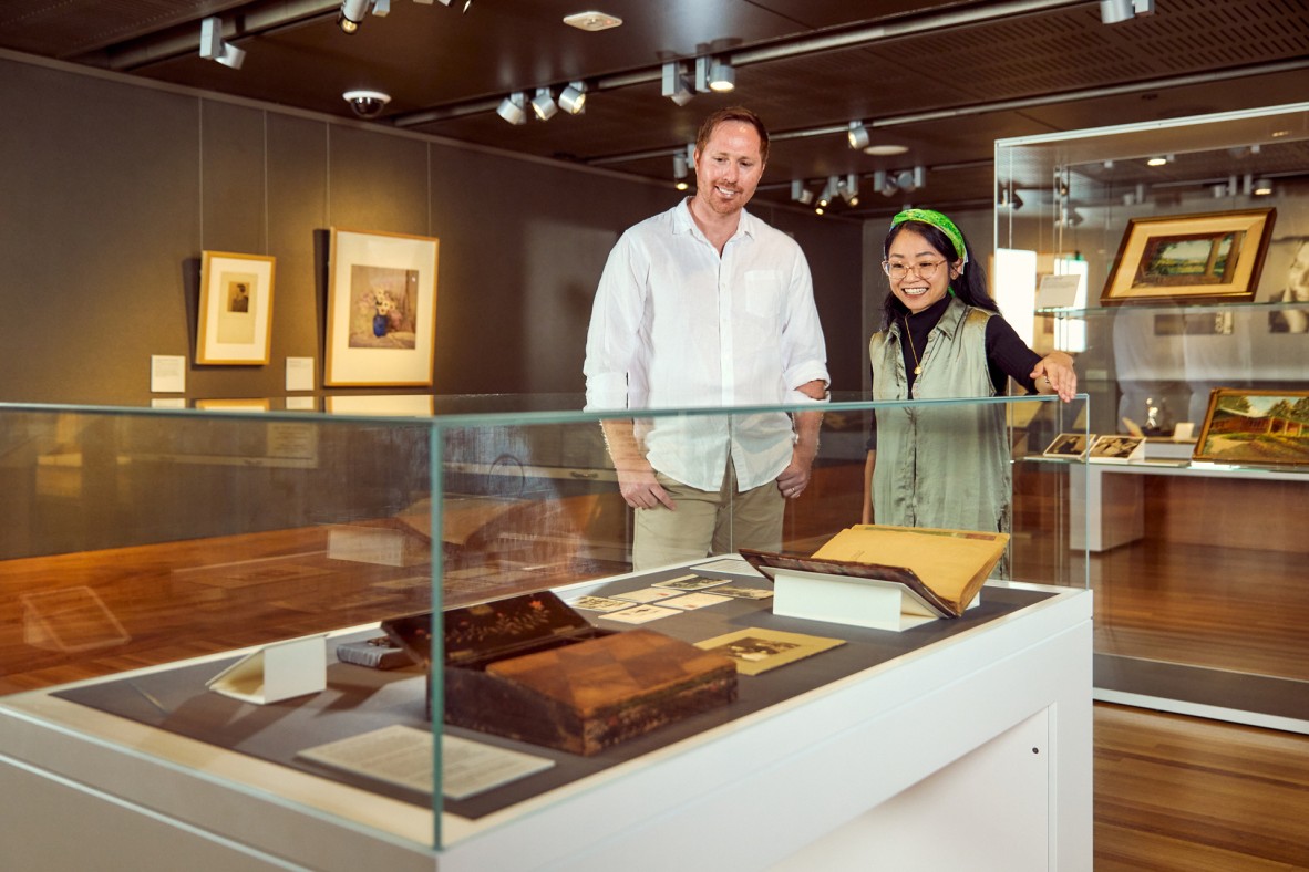 Two people looking at items in a glass case.