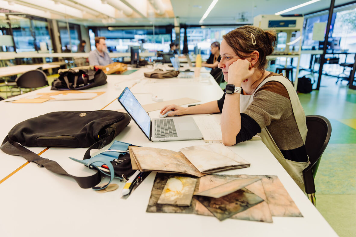 A photo of someone on a laptop and bookmaking components