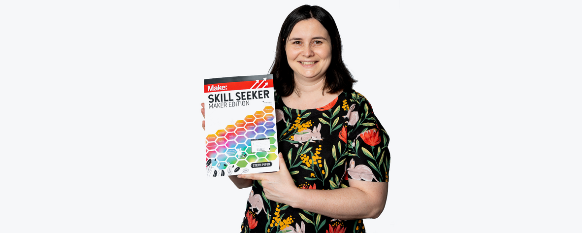 A photo of a woman holding a book called Skill Seeker; maker edition